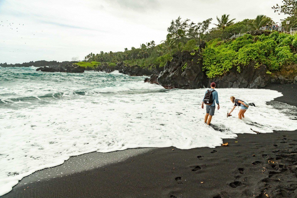 Road to Hana Black Sand Beach Visitors in Surf Waianapanapa Maui